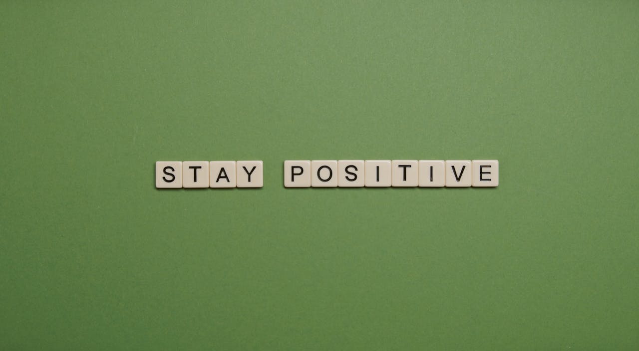 Home "Stay Positive" spelled with letter tiles on a green backdrop.